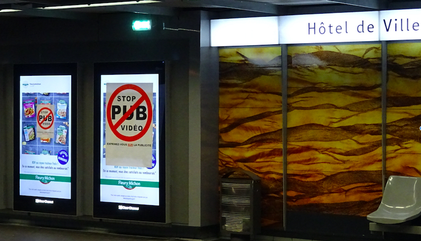 Deux écrans publicitaires tagué par des affiches "STOP PUB VIDEO" dans le métro à Lyon.